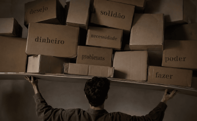 Homem de costas sustenta uma pilha irregular de caixas com palavras como desejo, solidão, dinheiro, poder, problemas, necessidade e fazer.