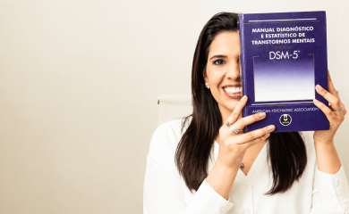 Imagem da Dra. Aline Rangel, médica psiquiatra, psicoterapeuta e sexóloga, segurando o Manual Diagnóstico e Estatístico de Transtornos Mentais, DSM-5. Foto utilizada como imagem destacada de artigo sobre avaliação psiquiátrica, diagnóstico e critérios clínicos.